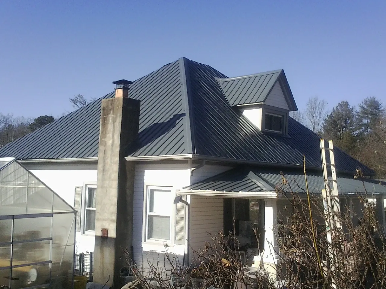 Dark blue standing seam metal roof on a white farmhouse with dormer — Slate & Tile Roof Repair by Roofing Brothers in Goleta