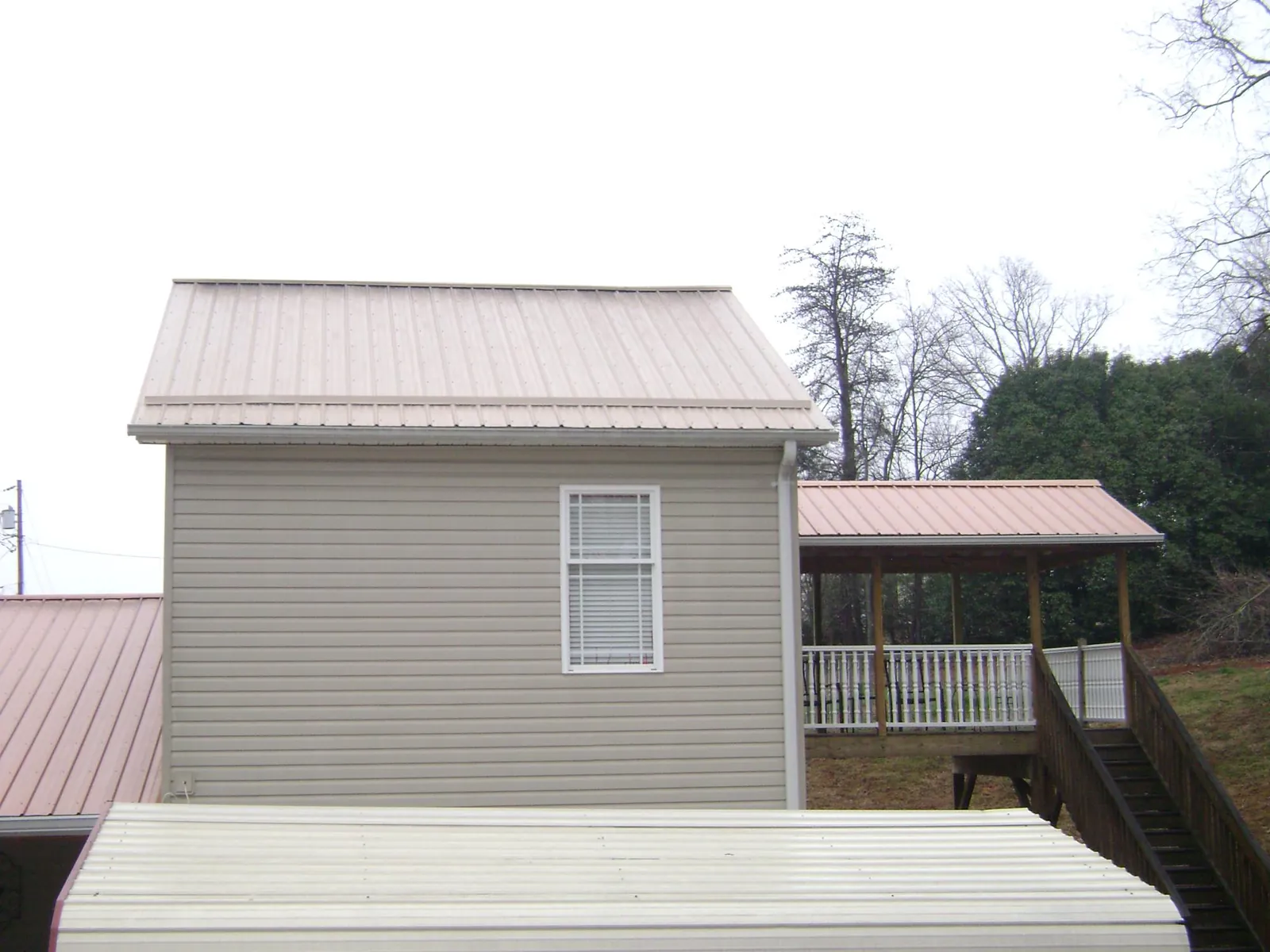 Tan metal roofs on a two story addition and attached porch, from a Roof Replacement job in Goleta